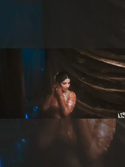 A moody, atmospheric portrait of Vedika getting ready. The dark tones and soft focus create a dreamy, intimate feel, capturing a private moment of preparation.