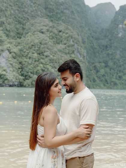 A romantic portrait of Kunal and Disha on the beach, with the lush green mountains of Thailand in the background.