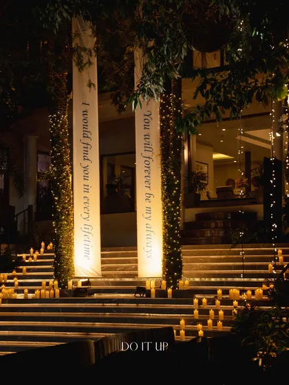 A romantic entrance for a Sangeet in Rishikesh. The steps leading to the venue are lined with hundreds of candles, and custom banners with love quotes create a deeply personal and dramatic welcome.