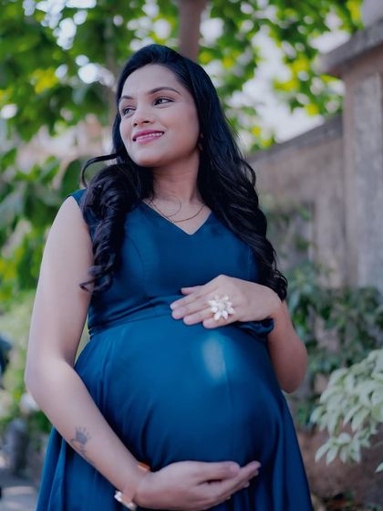 A beautiful solo outdoor portrait. The sunlight catches the rich blue of the gown, and the mom-to-be looks serene and confident.