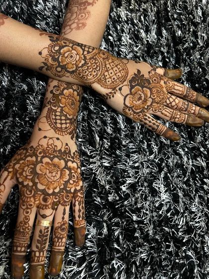 A beautiful semi-bridal design with crossed hands, showcasing complementary floral and paisley patterns. The dark paste looks striking against the textured background.