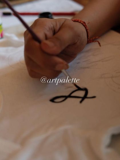 It all starts with a single brushstroke. Here is a close up of a guest carefully painting a personalized design onto a onesie, adding a touch of love to this special gift.