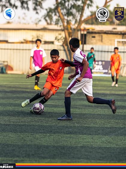 A player in orange tries to get past a defender in a fast paced Pune league match.