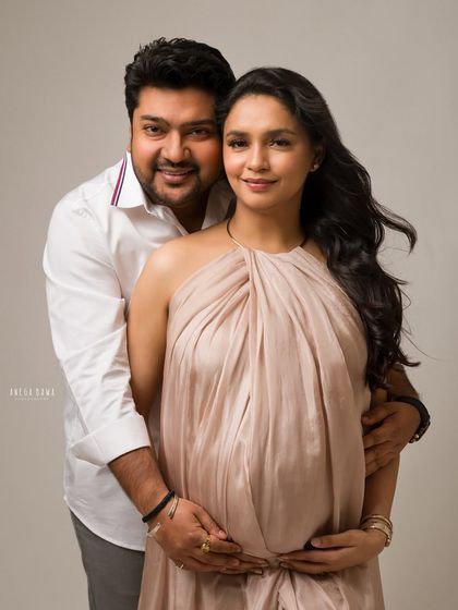 A classic couple's maternity portrait. They look directly at the camera, their connection evident in this beautifully composed, fine art style photograph.