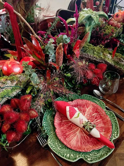 A place setting featuring a unique green leaf-patterned plate, contrasting beautifully with the rich red decor.