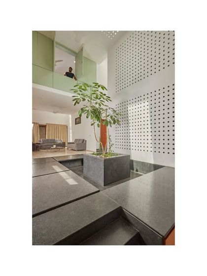 The central courtyard of the Vikas Residence features a large planter and a water body, creating a tranquil focal point. An upper-level opening provides a visual connection between floors.