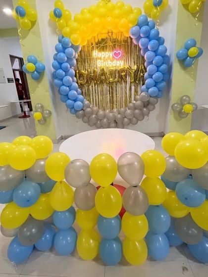 A Minion-inspired color-themed birthday in yellow, blue, and grey, with a balloon ring and a "Happy Birthday" neon sign.