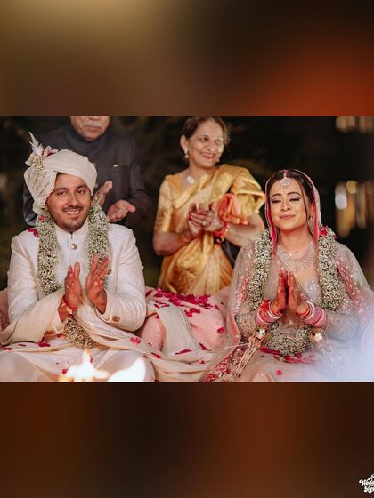 The couple seated by the sacred fire, their hands joined in prayer, a moment of peace and sanctity.