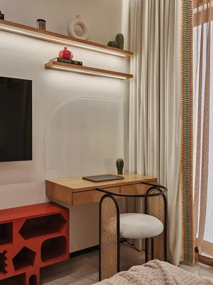 The room includes a practical study desk with a rattan chair and a fun, geometric orange TV unit for storage. The design is both kid-friendly and stylish.