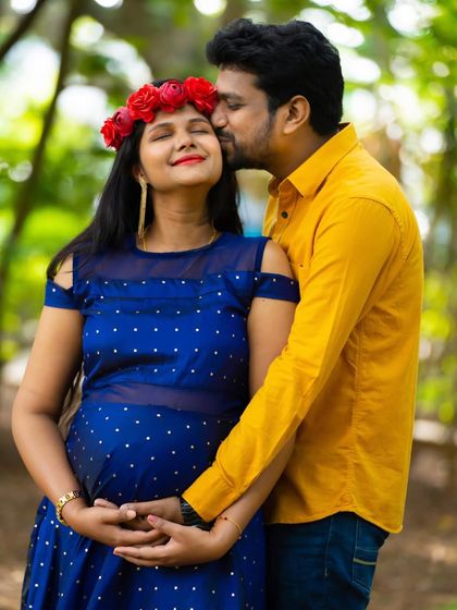 A sweet and tender moment between a couple in a park. The partner's gentle kiss on the forehead captures the love and excitement of their journey.