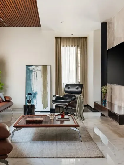 The family lounge is a composition of luxurious materials, including a timber-slatted ceiling, marble-clad wall, and rich leather sofa. The design creates a warm, inviting space for relaxation.