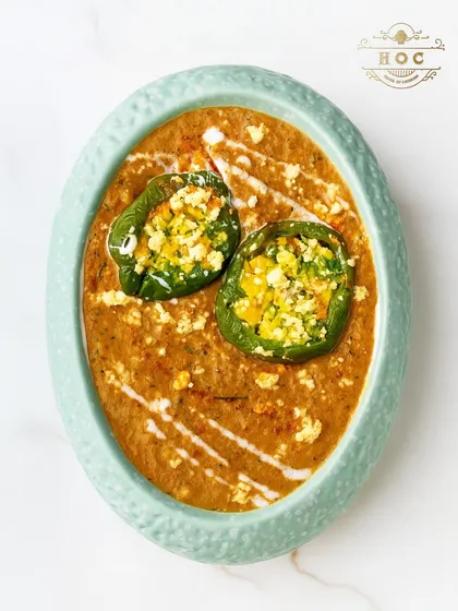 A creative take on a classic Indian dish. This preparation features bell peppers stuffed with spiced paneer, served in a rich, creamy gravy and presented in an elegant oval dish.