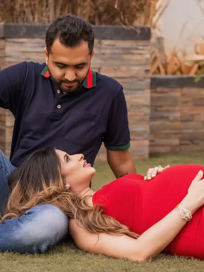 An outdoor session capturing a relaxed and intimate moment, with the mom-to-be resting her head on her partner's lap.