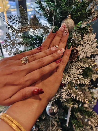 A festive Christmas manicure featuring red and green glitter with delicate hand-painted designs, perfect for celebrating the season.