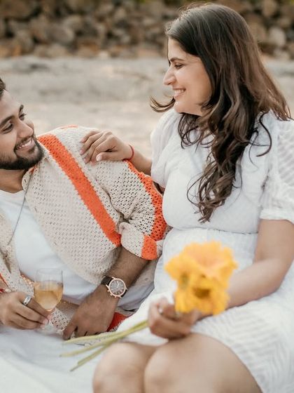 The couple enjoys a glass of champagne during their beach picnic. This photo captures a celebratory and relaxed moment, filled with smiles and conversation.