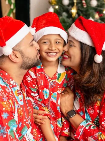 A picture of pure joy as parents shower their son with kisses, all wearing matching Santa hats.