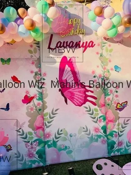 The main backdrop for the outdoor butterfly party, showing the custom print and the soft, multi-colored balloon garland.