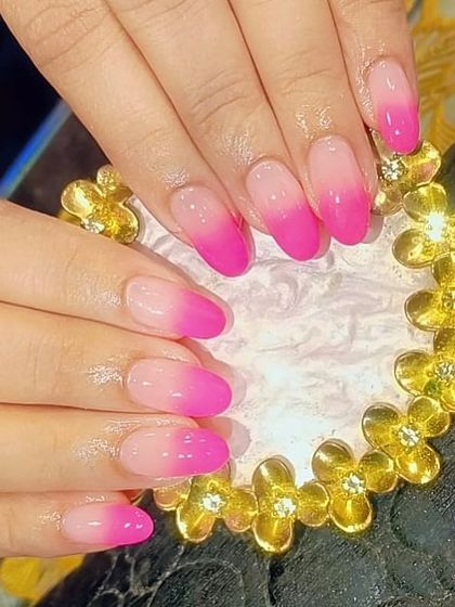 A vibrant pink ombre on oval-shaped nails, blending from a soft nude base to a bright, hot pink tip.