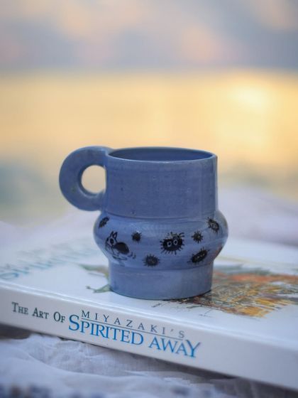 My Ghibli-inspired mug, resting on a book about the art of Spirited Away. It’s a piece made by a fan, for a fan, celebrating the magic of Hayao Miyazaki's worlds.