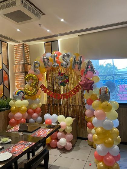 A complete view of the party decoration, with a shimmering gold backdrop and a balloon arch, creating a perfect photo corner.