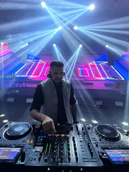 A focused moment at the DJ console during a destination wedding in Singapore. The lighting rig here was massive, creating beams that filled the entire hall.