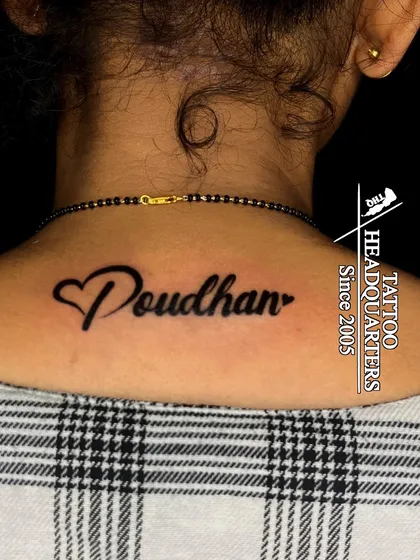 The name "Poudhan" with a heart integrated into the script, tattooed on the back of the neck.