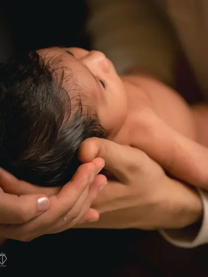 A close-up shot focusing on the newborn cradled safely in their parent's hands. This perspective emphasizes how small and precious they are, a detail parents cherish forever.