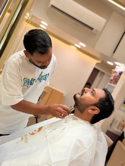 From a different angle, you can see the stylist defining the jawline with a trimmer. This step is essential for a structured and masculine beard shape.