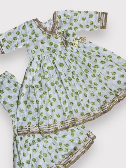 This soft cotton Angarkha and sharara set features a delicate green leaf print with subtle gold detailing. It’s an elegant and comfortable choice for festive gatherings.