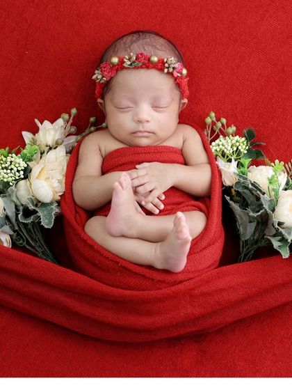 A beautiful pose with the baby wrapped in red and surrounded by white flowers. This adds a touch of elegance to a classic swaddled shot.