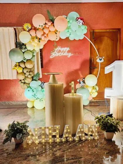 A simple and sweet jungle-themed decoration for a first birthday at home. This setup uses a balloon ring, a neon sign, and light-up letters to create a festive corner.