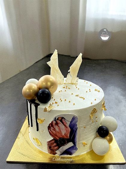 An abstract and artistic cake for a special celebration. This design features a modern art print, a chocolate drip, and a stylish arrangement of black, white, and gold spheres.