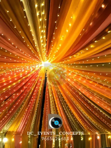 A mesmerizing ceiling decoration featuring colorful drapery and fairy lights radiating from the center. This kind of venue transformation creates a magical, tent-like atmosphere for any indoor or outdoor event.