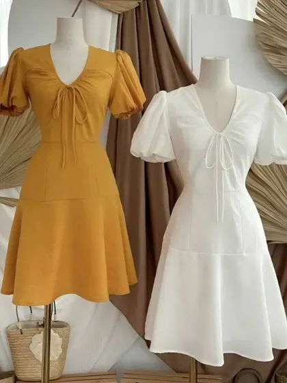 Showcasing variations of my custom A-line dress design. This style features a V-neck with a delicate tie-front detail and soft puff sleeves. I offer these tailored dresses in a range of colors, like this sunny yellow and classic white.