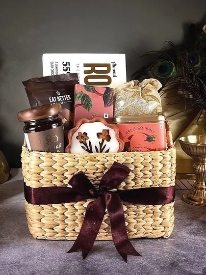 The 'Diwali Luxe' basket is a beautiful arrangement of premium items, including gourmet chocolates and dry fruits, presented in a rustic wicker basket with a rich brown ribbon.