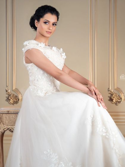A serene and elegant portrait of a model in a white wedding-style gown. The classical setting and soft lighting create a timeless and romantic image.