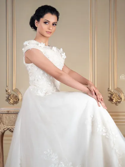 A serene and elegant portrait of a model in a white wedding-style gown. The classical setting and soft lighting create a timeless and romantic image.