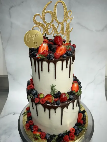 Who says you can't be sixty and sexy? This two-tiered drip cake, loaded with fresh berries, is all about celebrating milestones with personality and flair. We love making custom cakes that are as fun and vibrant as the people they're for.