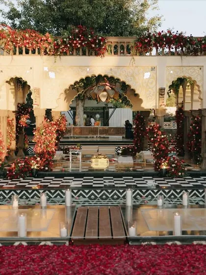 A stunning mandap at The Leela Palace Udaipur, featuring a dramatic black and white checkered floor and lush red floral arrangements. This design showcases our ability to blend bold, modern patterns with classic romantic decor.