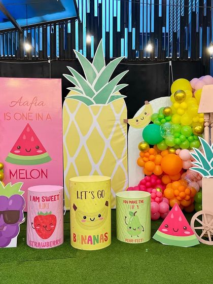 The full setup for Aafia's 'One in a Melon' first birthday. The vibrant fruit characters and colorful balloon garland create a fun and fresh atmosphere perfect for a summer party.
