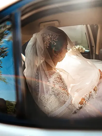 A creative shot of the bride in her car, with the groom's reflection visible on the window.