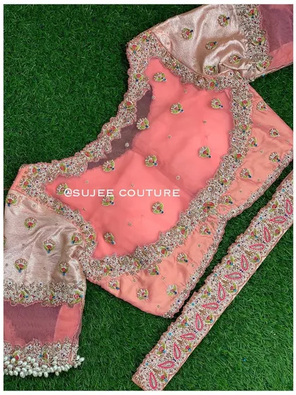 A detailed view of the peach blouse, showing the scalloped neckline and the fine zardozi work. The sleeve cuffs are adorned with a heavy bunch of pearl tassels.