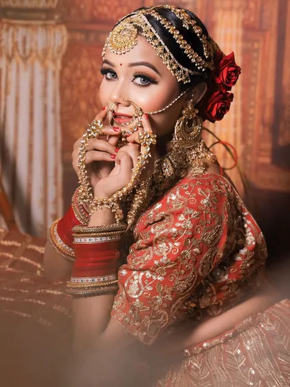 A playful shot of the bride, highlighting the beautiful matha patti and oversized jhumkas of her golden jewellery set.