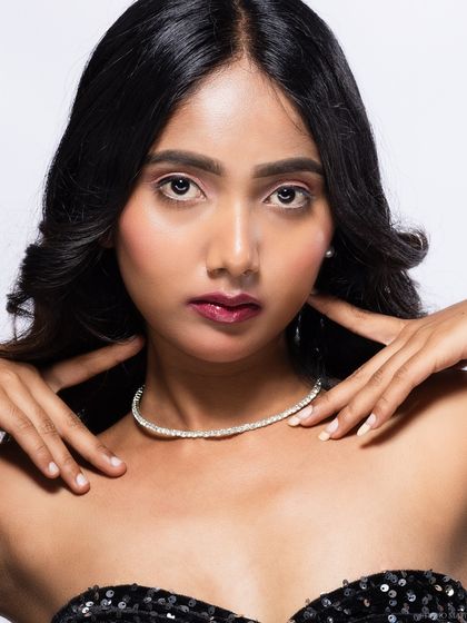 A clean beauty headshot focusing on the model's clear skin and a simple, elegant diamond necklace. This is a classic portrait style.