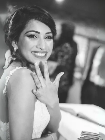 A happy bride shows off her engagement ring. This black and white candid shot captures her brilliant smile and the excitement of the moment.