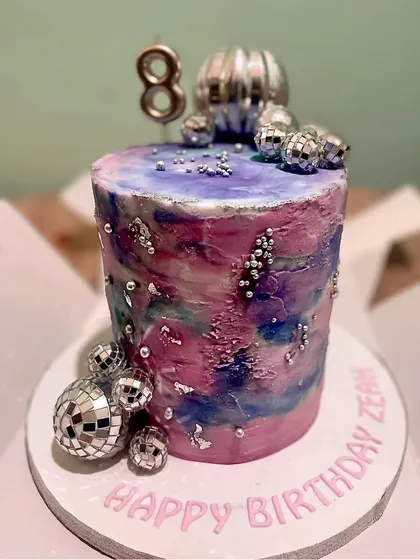 A stunning galaxy-themed cake with silver disco balls, perfect for an 8th birthday celebration.