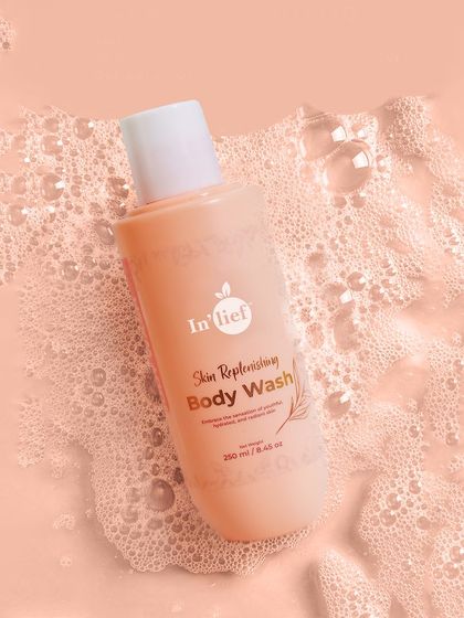 An aerial shot of In'lief Body Wash surrounded by soft foam. This top-down perspective provides a clean, graphic look that focuses on the product's packaging and the sensory experience of using it.