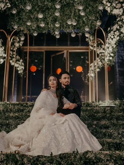 A grand, wide-angle shot of the couple on their beautifully decorated Sangeet stage.