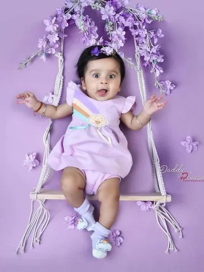 Capturing the playful personality of a baby girl as she makes a funny face while sitting on a floral swing. These candid moments are just as precious as the posed ones.