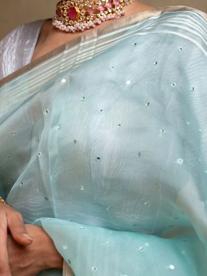 The scattered mirror work on the blue organza saree catches the light beautifully, creating a magical effect.